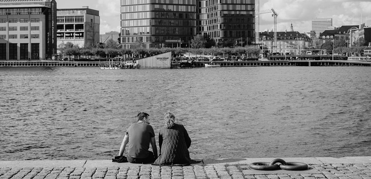 To personer med ryggen til kigger ud over et havnemiljø